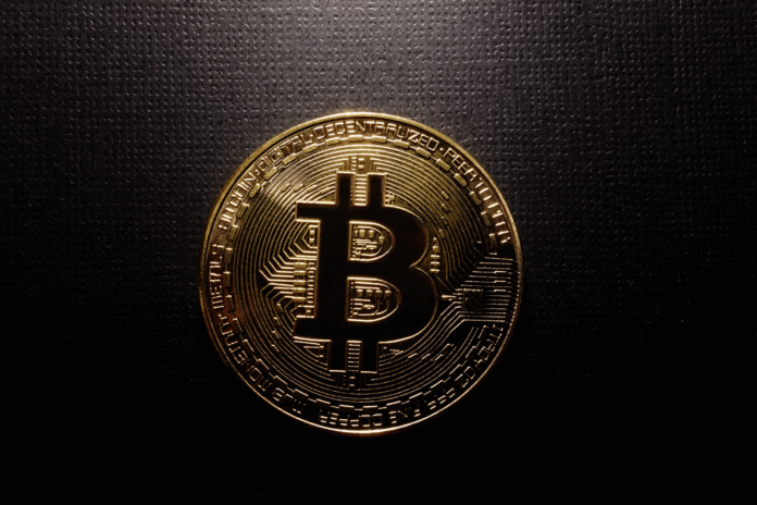 Zlatna Bitcoin kovanica u fokusu na tamnoj pozadini
